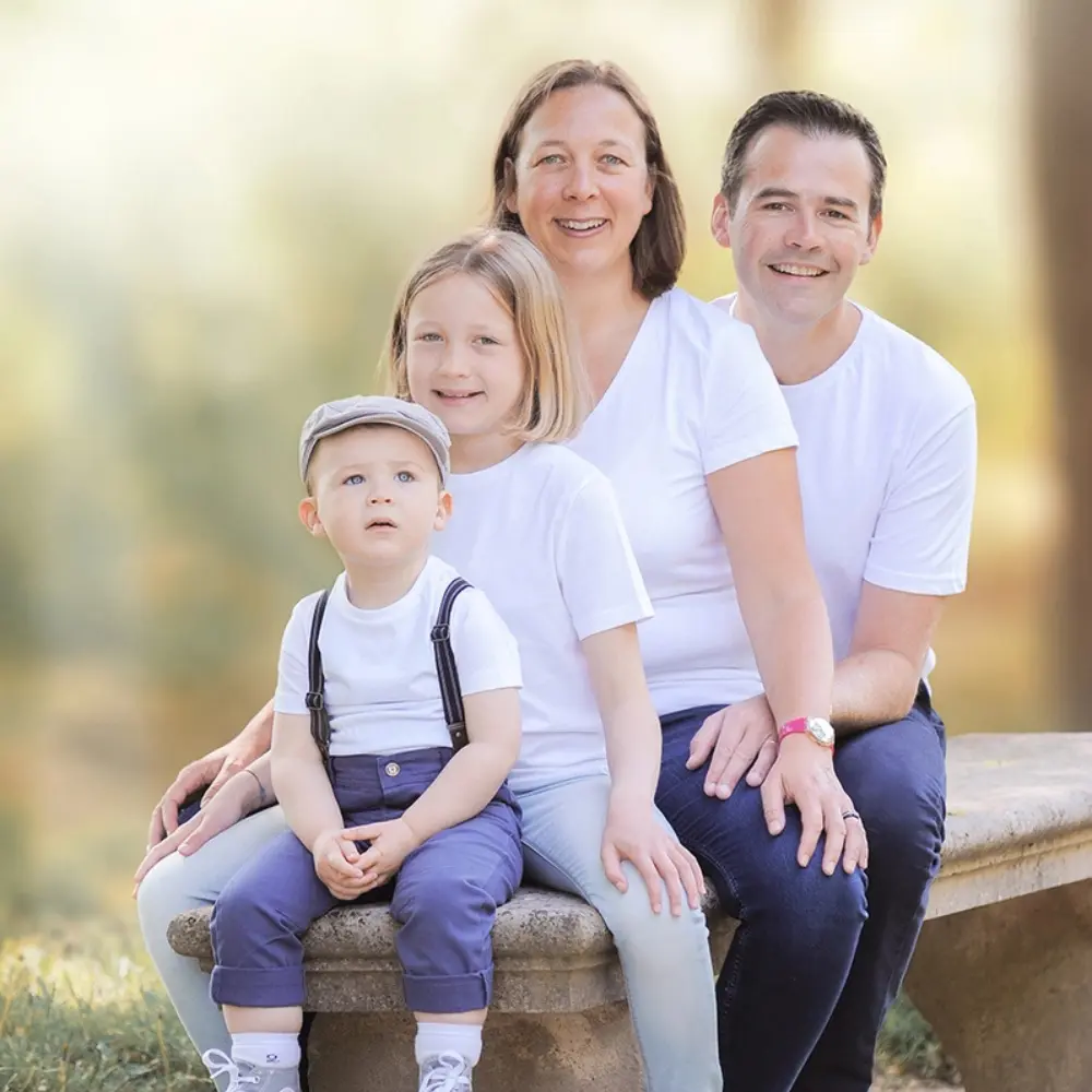 Une famille assise sur un banc les uns derrière les autres, les enfants sont au premier plan et les parents à l'arrière plan. Photo capturé à Bergerac en Dordogne.