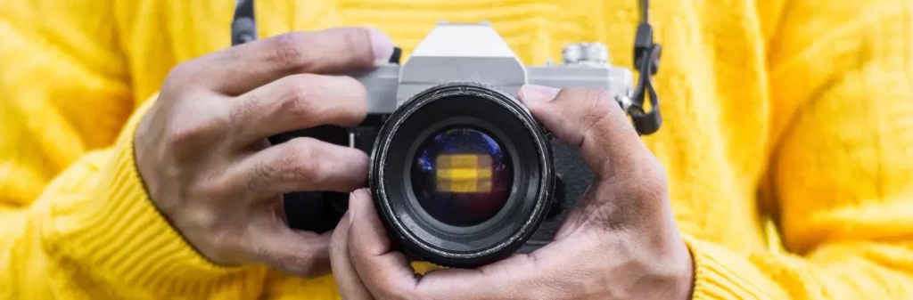 Un photographe de face avec son appareil photo, prenant une photo dans le vieux Bergerac en Dordogne.